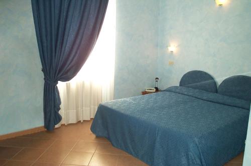 a bedroom with a blue bed and a window at Hotel La Milanese in Pietra Ligure