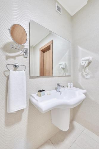 a bathroom with a white sink and a mirror at Praga Hotel in Tashkent