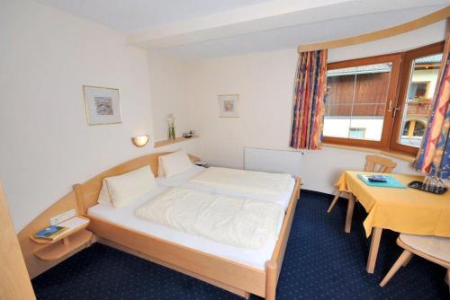 a bedroom with a large bed and a desk at Apart Hotel Garni Kofler in Fiss