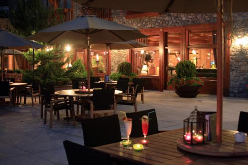 an outdoor restaurant with tables and chairs and umbrellas at Sport Hotel Village in Soldeu