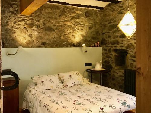 a bedroom with a bed in a stone wall at Casa Mingot SXVI Anciles Benasque in Anciles