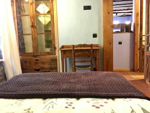 a bedroom with a bed and a table and a refrigerator at Casa Mingot SXVI Anciles Benasque in Anciles