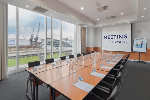 a large meeting room with a long table and chairs at Novotel London Excel in London