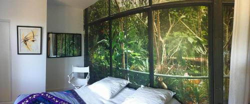 - une chambre dotée d'une grande fenêtre avec une fresque murale représentant la jungle dans l'établissement Gîte horizon mer et campagne, à Pornic