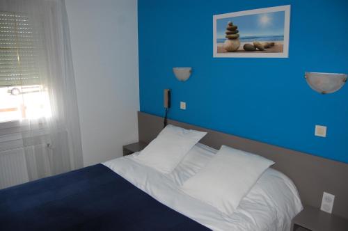 1 dormitorio con 1 cama con pared azul en Relais Saint Michel, en Saint-Michel