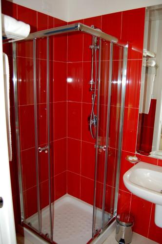 a red tiled bathroom with a shower and a sink at Hotel Budoni Beach in Budoni