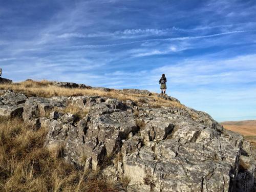 a man standing on top of a large rock at Snug Oak Hut with a view on a Welsh Hill Farm in Brecon