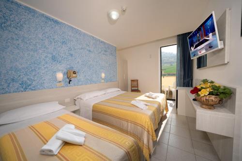 Una habitación de hotel con dos camas y un televisor de pantalla plana. en Hotel Florida, en Silvi Marina