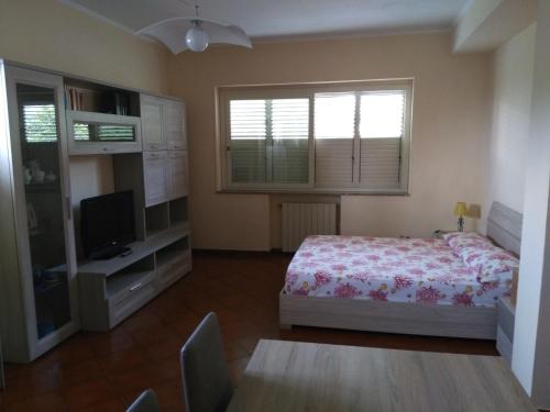 1 dormitorio con 1 cama, TV y ventana en B&B Mantinera, en Praia a Mare
