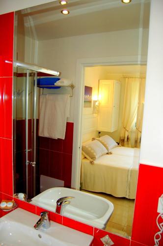 a bathroom mirror with a sink and a bedroom at Hotel Budoni Beach in Budoni
