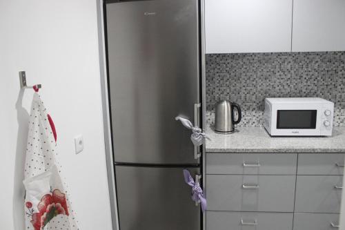 a stainless steel refrigerator in a kitchen with a microwave at Casa da Avó Lurdes in Póvoa de Varzim