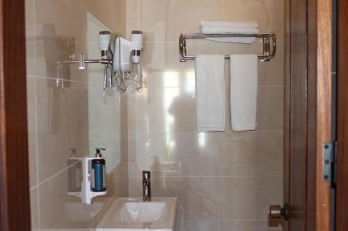 uma casa de banho com lavatório, espelho e toalhas em Guest House - Duna Parque Group em Vila Nova de Milfontes
