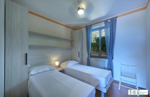 2 Betten in einem Zimmer mit Fenster in der Unterkunft Casa Iris in Perledo