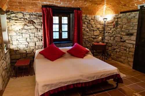 sypialnia z dużym łóżkiem z czerwonymi poduszkami w obiekcie Agriturismo La Verena w mieście Vesime