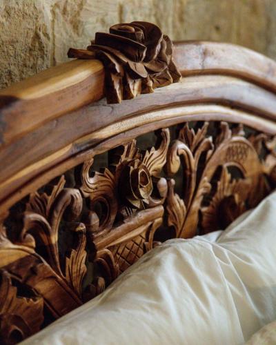 a wooden bed frame with a wooden carving on it at The 3Cities Auberge in Cospicua