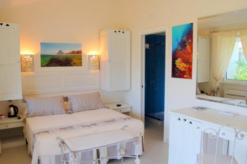 a white bedroom with a bed and a sink at Hotel Budoni Beach in Budoni