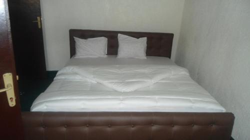 a bed with white sheets and pillows on it at AIRPORT INN MOTEL in Kigali