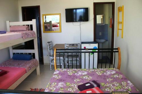 a room with bunk beds and a table and a tv at Joaquina 433 - Pousada Floripa in Florianópolis