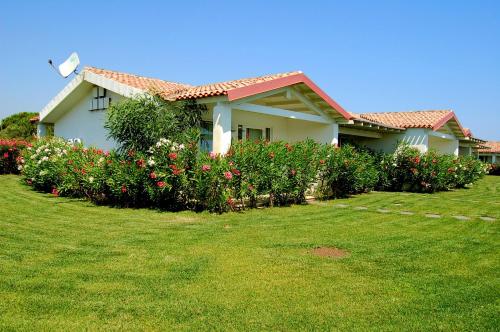 a house with flowers in front of a yard at Hotel Budoni Beach in Budoni