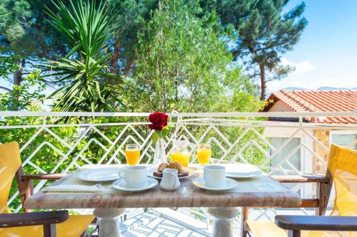 キパリシアにあるIrida Beach Resort Suitesのテーブル(バラ付)とオレンジジュース2杯