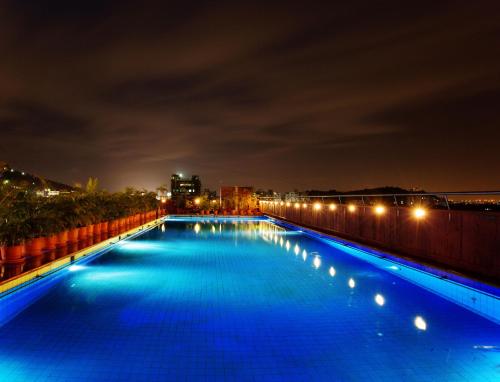a large swimming pool with blue lights at night at E Square The Fern, Pune in Pune