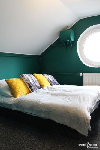 a bed with pillows in a room with a window at Dworek Zakopane in Zakopane