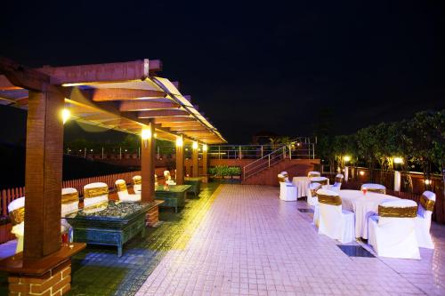 a patio with white tables and chairs at night at E Square The Fern, Pune in Pune