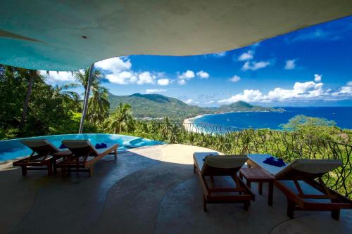 a pool with chairs and a view of the ocean at Monkey Flower Villas in Koh Tao