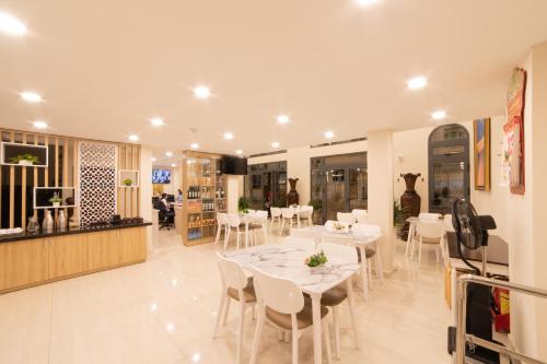 una sala da pranzo con tavoli bianchi e sedie bianche di Silent Night Dem Lanh Hotel a Da Lat