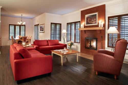 a living room with red furniture and a fireplace at Auberge du Lac-à-l'Eau-Claire in Saint-Alexis-des-Monts