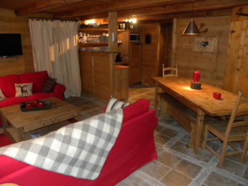 un salon avec un canapé rouge et une table en bois dans l'établissement CHALET GRINCH 90m2, 3 Sdb, skis aux pieds, wifi, à Tignes