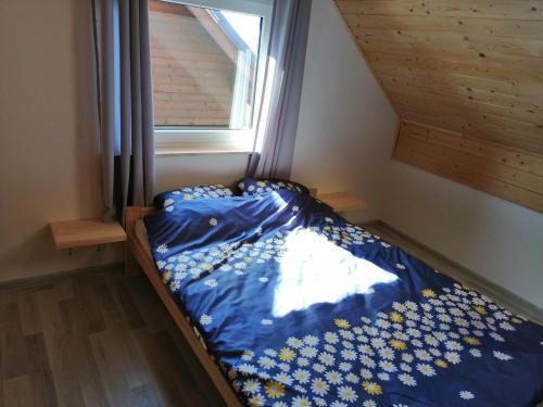 a bedroom with a bed with a blue comforter and a window at Domki Pod Gwiazdami in Władysławowo