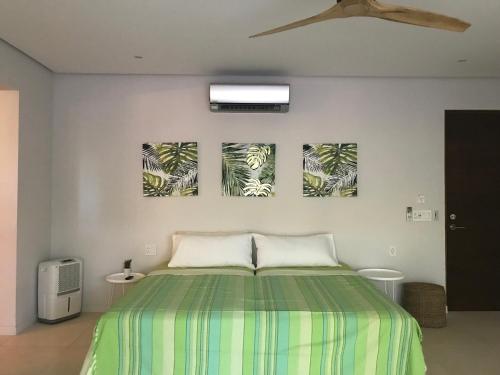 ein Schlafzimmer mit einem Bett mit drei Gemälden an der Wand in der Unterkunft Casa Papito in Potrero