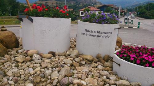 two buckets of flowers sitting on a pile of rocks at La Quintana de Doña Leonor in Arriondas