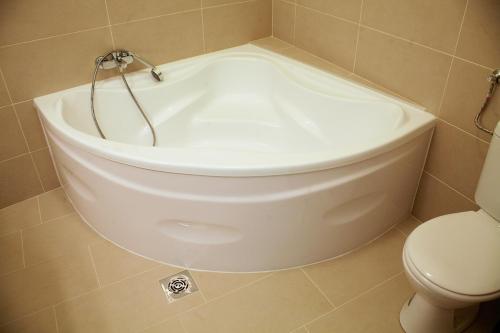 a white bath tub in a bathroom with a toilet at Five Season's Apartment in Budapest