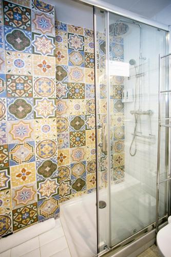 a bathroom with a shower with a mosaic tile wall at Graffiti Suites Málaga in Málaga