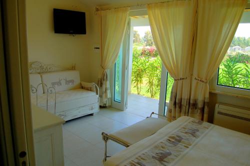 a bedroom with a bed and a balcony with a television at Hotel Budoni Beach in Budoni