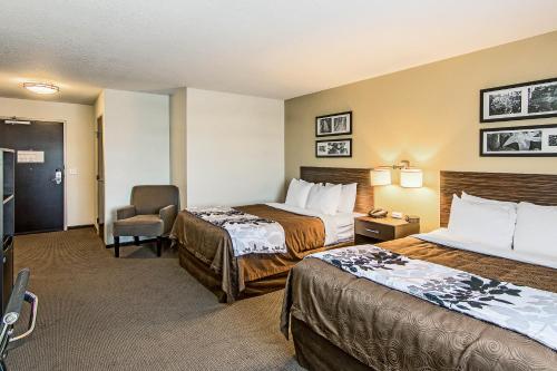 una habitación de hotel con 2 camas y una silla en Sleep Inn & Suites West-Near Medical Center, en Rochester