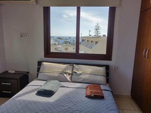 a bed in a bedroom with a large window at Elena Court Apartments in Ayia Napa