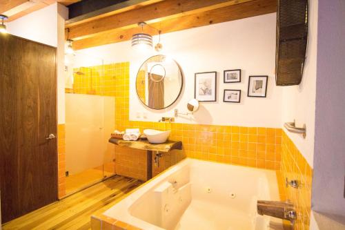 a bathroom with a tub and a sink and a mirror at Mesón De Leyendas Breakfast & Downtown in Valle de Bravo