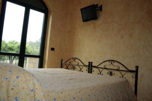a bedroom with a bed and a tv on the wall at Cascina Concetta in Pizzo