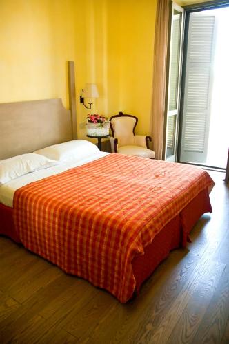 a bedroom with a large bed with an orange blanket at Locanda Delle Mura Anna De Croy in Magliano in Toscana