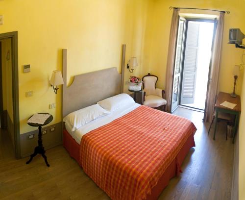 a bedroom with a large bed with a orange blanket at Locanda Delle Mura Anna De Croy in Magliano in Toscana