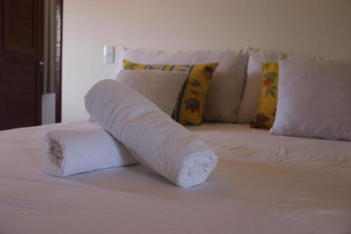 a rolled up towel on top of a bed at Flat's Portal do Sol-SMG in São Miguel do Gostoso