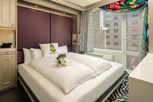a bedroom with a white bed with a teddy bear on it at Staypineapple, An Artful Hotel, Midtown New York in New York