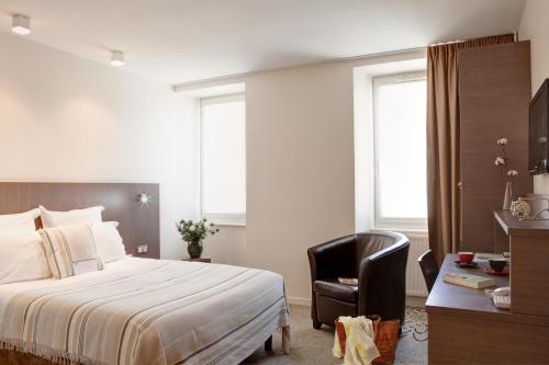 a bedroom with a bed and a desk and a chair at Hôtel Le Benhuyc in Binic-Etables-sur-Mer