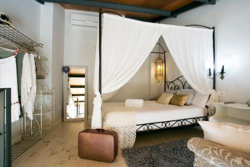 1 dormitorio con cama con dosel y maleta en Graffiti Suites Málaga, en Málaga