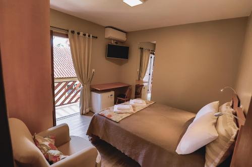 um quarto de hotel com uma cama e uma varanda em Cammino Della Serra em Canela