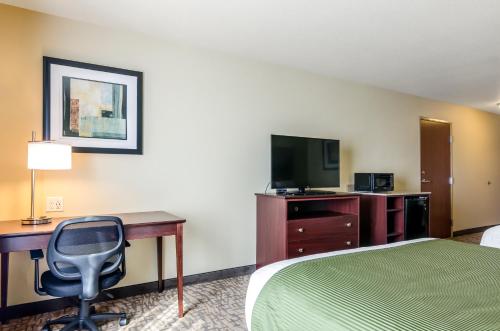 a hotel room with a bed and a desk and a chair at Cobblestone Hotel & Suites - Torrington in Torrington