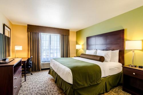 a hotel room with a large bed and a desk at Cobblestone Hotel & Suites - Torrington in Torrington